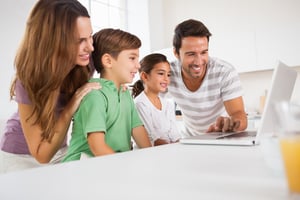 Happy family using a laptop in kitchen